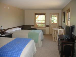 Habitación de hotel con 2 camas y TV de pantalla plana. en August Lodge Cooperstown, en Hartwick Seminary