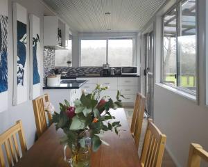 a kitchen with a table with a vase of flowers on it at Cherswood Farm in Balbarrup