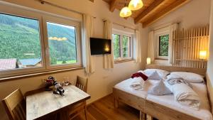 a bedroom with a bed and a table and windows at Montanara Apartment & Zimmer in Ramsau am Dachstein