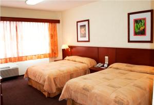 a hotel room with two beds and a window at Hotel Marcella Clase Ejecutiva in Morelia