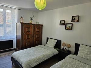 a bedroom with two beds and a wooden cabinet at Appartement Le Jardin Imaginaire in Champagnole