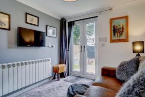 a living room with a couch and a sliding glass door at Robins Rest by Winterton Cottages in Hemsby