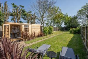 a small backyard with a shed with a table and chairs at Robins Rest by Winterton Cottages in Hemsby