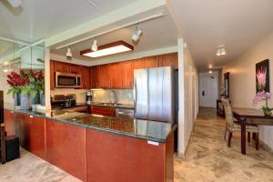 a kitchen with a stainless steel refrigerator and a table at Kihei Surfside, #511 condo in Wailea