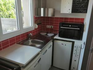 a small kitchen with a sink and a microwave at Maison Halle in Pouxeux