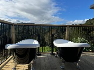 a balcony with two bath tubs on a deck at Te Mata Retreat in Tapu +1 photo