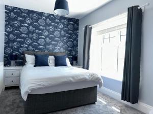 a bedroom with a large bed with a blue wall at White Anchor Anglesey in Newborough
