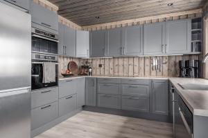 a kitchen with gray cabinets and a wooden ceiling at Lyxig stuga på Branäsberget in Sysslebäck +30 photos