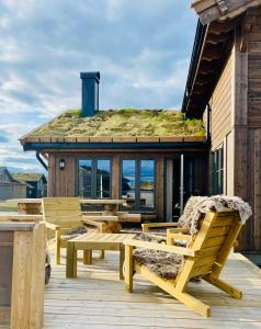 a wooden deck with benches and a building with a grass roof at Lyxig stuga på Branäsberget in Sysslebäck