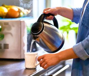 a woman pouring a tea kettle into a cup at ARK HOTEL MELAWATI in Kuala Lumpur