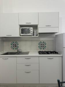 a white kitchen with a sink and a microwave at Casa Orchidea in Taormina