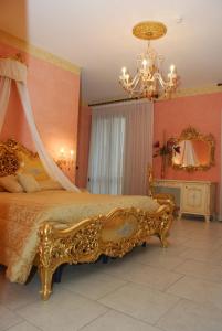 een slaapkamer met een gouden bed en een kroonluchter bij Hotel Riva Del Sole in Porto Cesareo