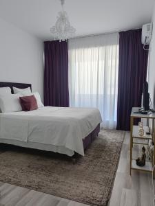 1 dormitorio con 1 cama grande y cortinas moradas en Safirului apartment, en Bragadiru