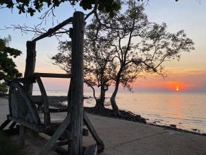 a wooden bench sitting on the beach with a sunset at Koh Chang Bailan Beach Resort in Ko Chang