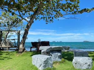 a table and chairs under a tree next to the ocean at Koh Chang Bailan Beach Resort in Ko Chang