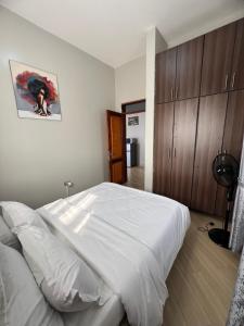 a bedroom with a large white bed and wooden cabinets at Skyline residence Kyanja in Kampala