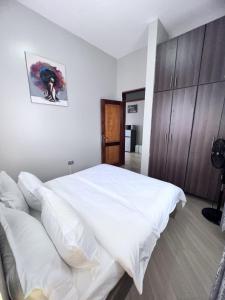 a bedroom with a large white bed and wooden cabinets at Skyline residence Kyanja in Kampala