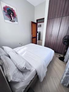a bedroom with a large bed with white sheets at Skyline residence Kyanja in Kampala