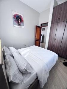 a bedroom with a large bed with white sheets at Skyline residence Kyanja in Kampala