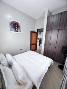 a bedroom with a large white bed and wooden cabinets at Skyline residence Kyanja in Kampala
