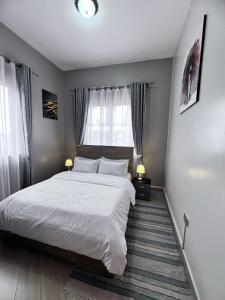 a bedroom with a large white bed and a window at Skyline residence Kyanja in Kampala