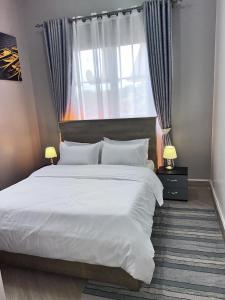 a bedroom with a large white bed and a window at Skyline residence Kyanja in Kampala