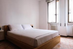 une chambre avec un lit avec des draps blancs et des fenêtres dans l'établissement Flora Inn, Paglia 2 - Nel cuore del centro città, à Bergame