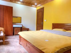 a bedroom with a bed and a yellow wall at Thanh Truc House in Sa Pa