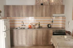 a kitchen with wooden cabinets and a table and a white refrigerator at Takis Seaside Apartment in Kýthira