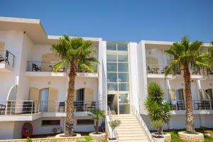 a building with palm trees in front of it at Royal Blue Hotel in Dhërmi