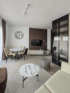 Una sala de estar con una mesa y un reloj en la pared. en Juzni Horizont Apartments, en Sutomore