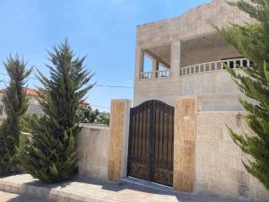 a stone house with a gate and two trees at Jerash air apartment in Jerash