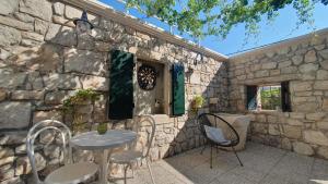 un bâtiment en pierre avec une table et des chaises sur une terrasse dans l'établissement Holiday house - Dvori Vlahovici, à Opuzen