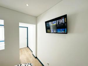 een kamer met een flatscreen-tv aan de muur bij Guest House DML in Aveiro
