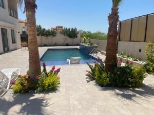 a swimming pool with two palm trees and flowers at Deadsea Elite First floor shared swimming pool in Sowayma