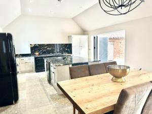 a kitchen with a wooden table with chairs and a refrigerator at Papillon in Gamston