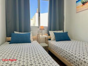 two beds in a small room with blue curtains at Casas Pedro & Agata in Morro del Jable