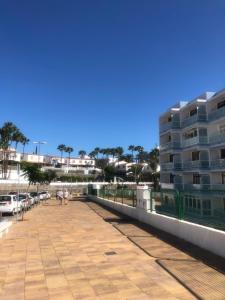 a boardwalk next to a parking lot with a building at Yumbo-Europa Apartamentos in Playa del Ingles