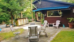 a patio with chairs and a table in front of a house at Het Houten Boshuisje in Hattemerbroek +8 photos