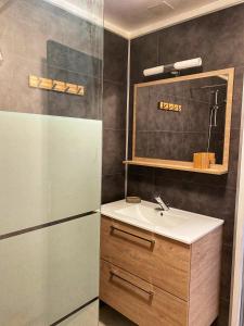 a small bathroom with a sink and a refrigerator at La Butinerie in Baron