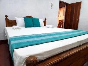 a bedroom with a large bed with blue and white sheets at Mango Villa Hiriketiya in Dickwella