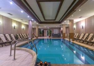 a pool in a hotel with chairs around it at Студио в хотел Мария Антоанета in Bansko