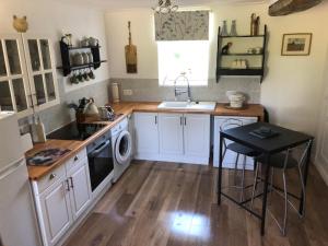 a kitchen with white cabinets and a sink and a dishwasher at The Stable in Sourdeval