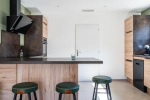 a kitchen with a counter with two green stools at Superbe villa climatisée in Connaux
