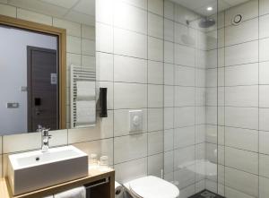 ein Badezimmer mit einem Waschbecken, einem WC und einem Spiegel in der Unterkunft Storm Hotel by Keahotels in Reykjavík