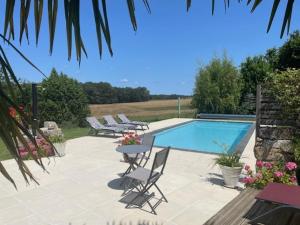 a swimming pool with chairs and a table next to it at Lime Tree Farmhouse in Saint-Saud-Lacoussière