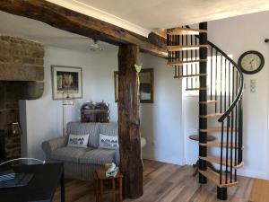a living room with a spiral staircase and a couch at The Stable in Sourdeval