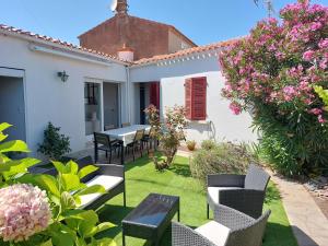 einen Garten mit einem Tisch, Stühlen und Blumen in der Unterkunft Maison de pêcheur - Quartier Croix de Vie in Saint-Gilles-Croix-de-Vie
