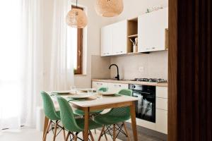 a kitchen with a table and green chairs at Verdeacqua Home in Castellammare del Golfo
