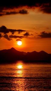 爱妮岛Coconut Cottages El Nido的夕阳西下,山 ⁇ 在背后